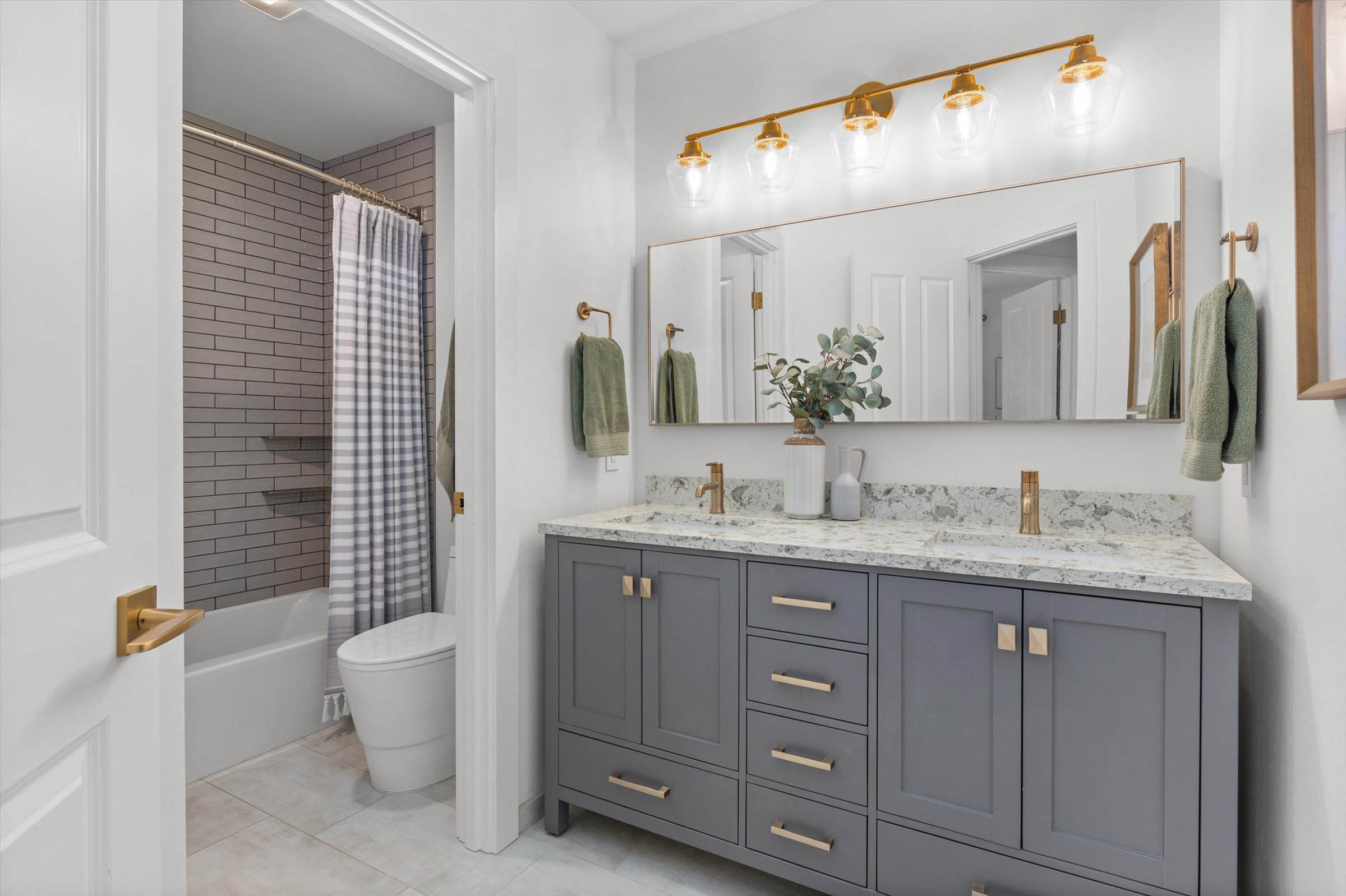 Enhance your bathroom with a chic gray vanity and luxurious gold fixtures during a stunning Bathroom Remodel.