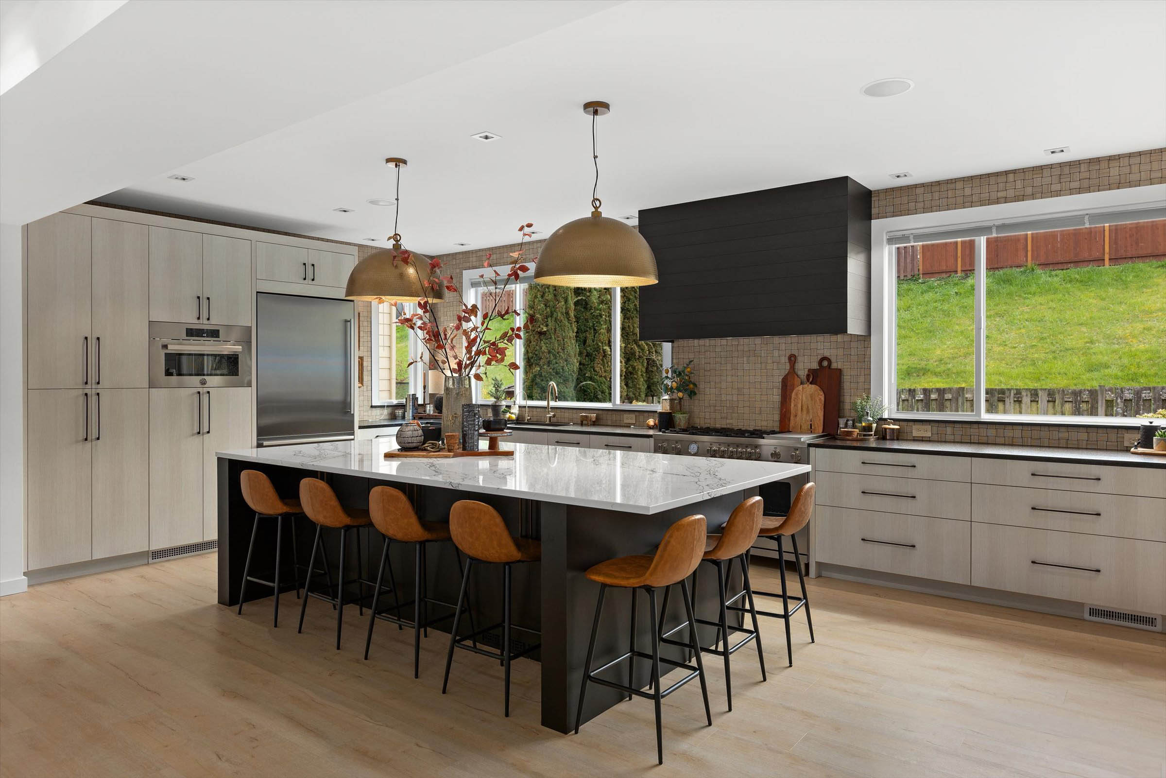 Stylish kitchen boasts quartz island, comfy stools, and sleek appliances.