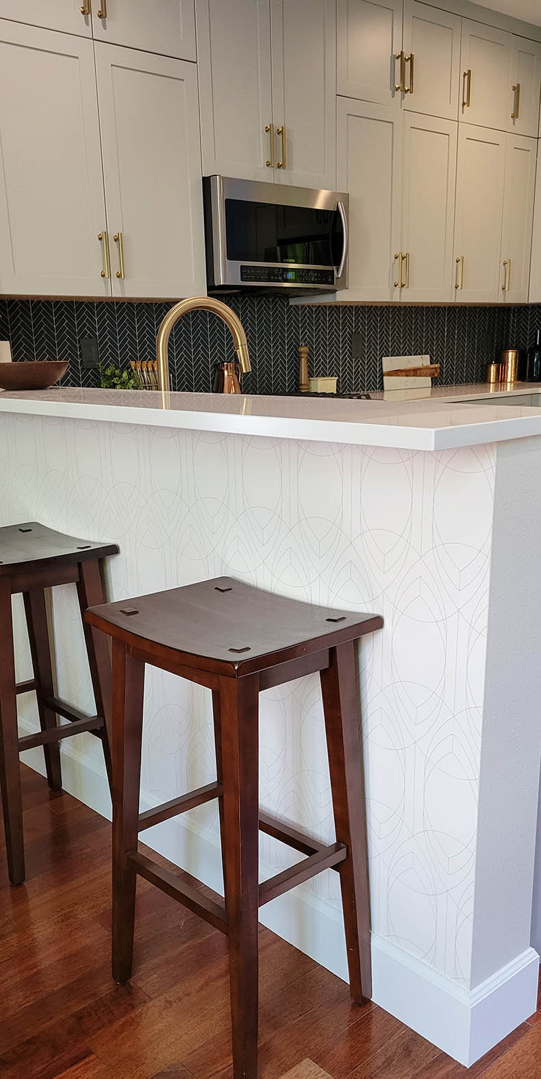 Kitchen remodel white counter with dark wooden stools over cherry hardwood floors.